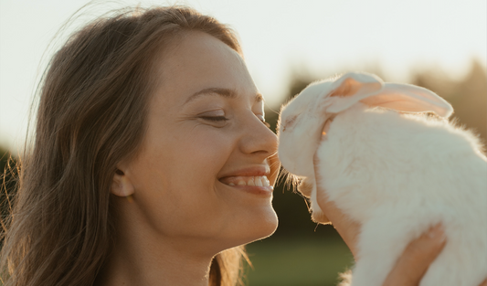 Beautiful smiling white woman with straight brown hair holding a white rabbit.